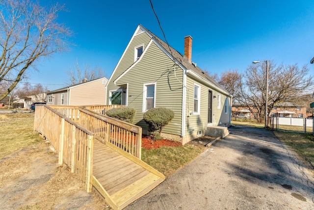 view of side of home featuring a chimney and fence