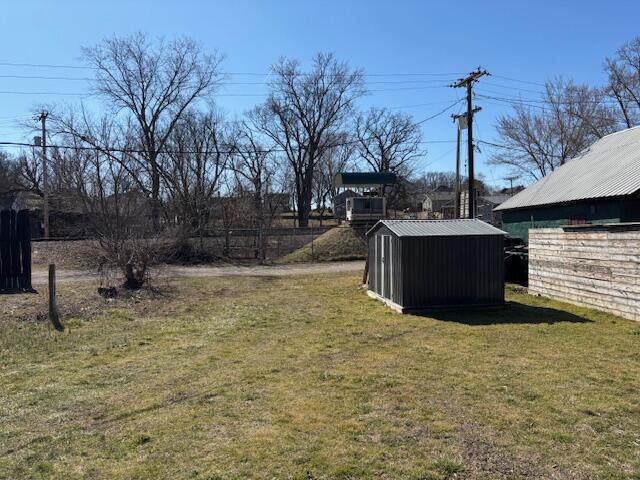 view of yard with a storage shed, an outbuilding, and fence