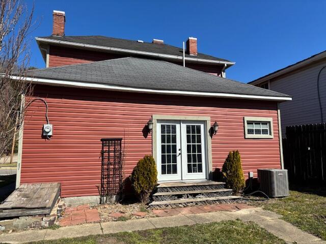 back of house featuring central AC unit, french doors, fence, and a chimney