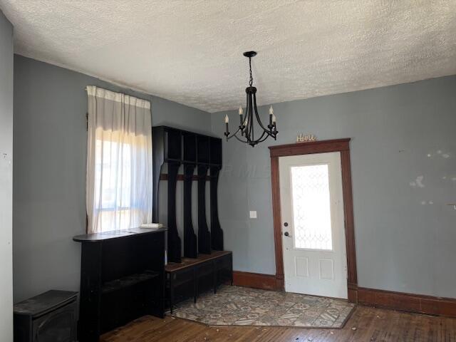 foyer entrance featuring a chandelier, a textured ceiling, baseboards, and wood finished floors