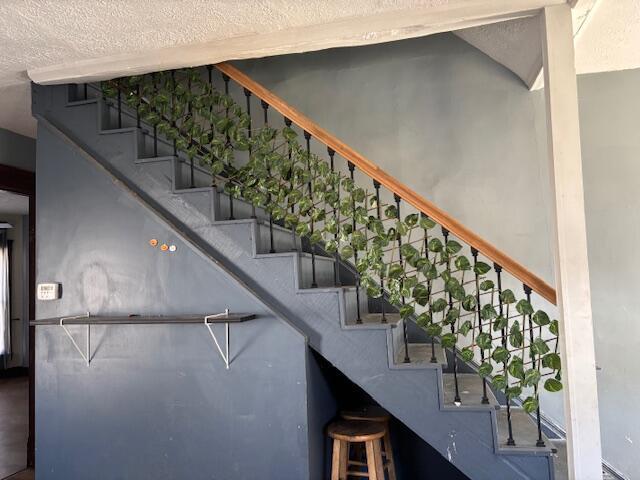 stairway featuring a textured ceiling