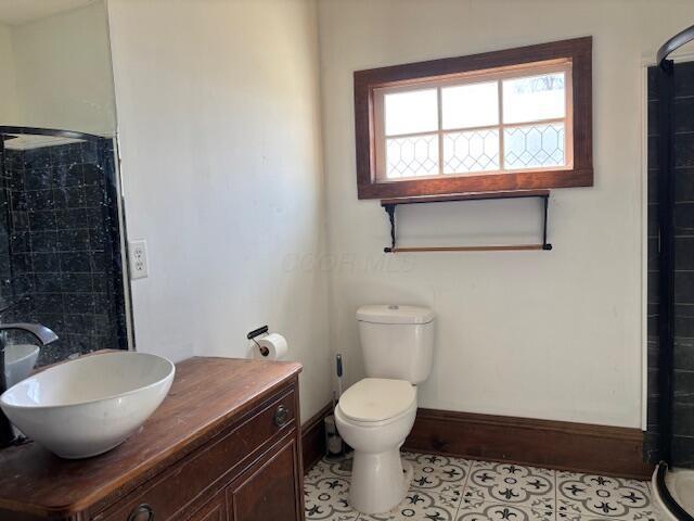 full bathroom with baseboards, tiled shower, toilet, and tile patterned flooring