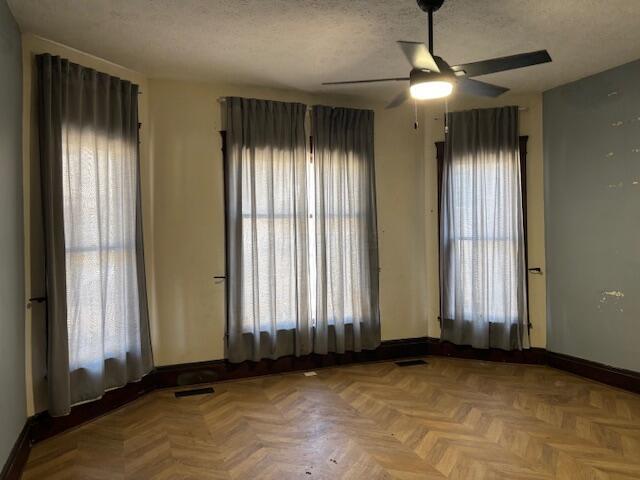 unfurnished room featuring a wealth of natural light, a textured ceiling, and baseboards