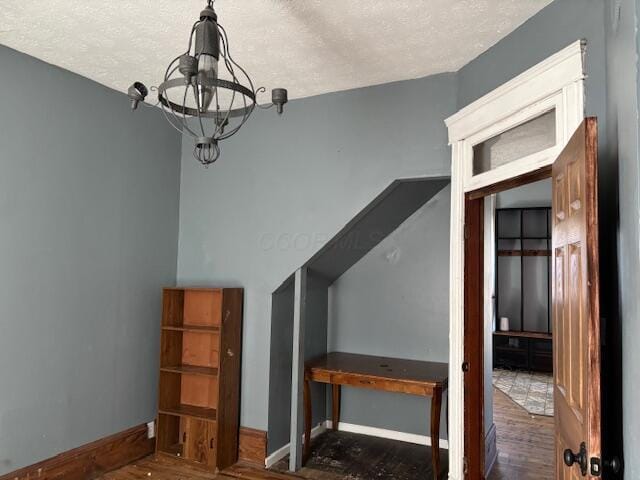 bonus room featuring a chandelier, a textured ceiling, and baseboards