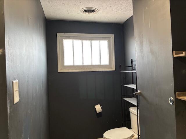 bathroom featuring visible vents, a textured ceiling, and toilet