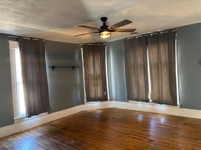 unfurnished room featuring a ceiling fan, wood finished floors, baseboards, and a textured ceiling