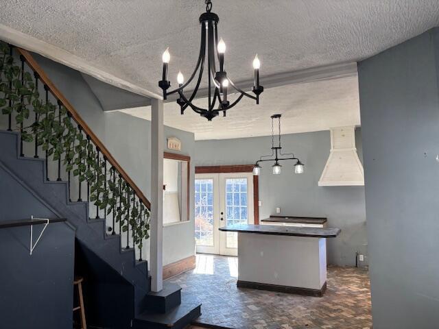 kitchen featuring a center island, premium range hood, french doors, an inviting chandelier, and a textured ceiling