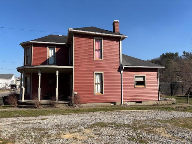 rear view of property with a porch and a chimney