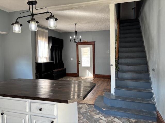 kitchen featuring baseboards, butcher block countertops, hanging light fixtures, white cabinets, and a chandelier