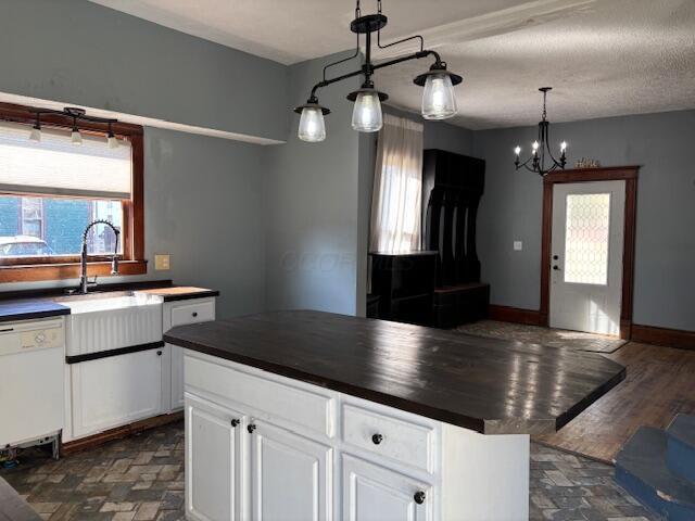 kitchen with a textured ceiling, white cabinets, white dishwasher, and pendant lighting