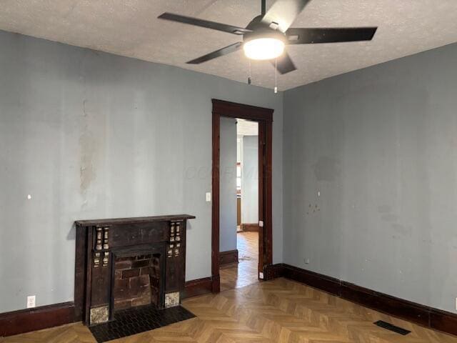 living area featuring a fireplace with flush hearth, visible vents, baseboards, and a textured ceiling