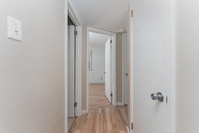 hallway featuring light wood-style flooring and baseboards