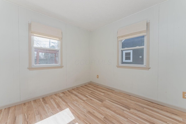 spare room with baseboards and wood finished floors