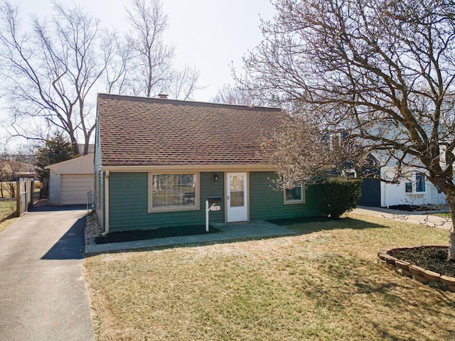 view of front facade featuring a garage, roof with shingles, an outdoor structure, and a front yard