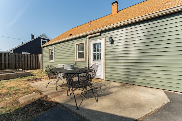 view of patio featuring a vegetable garden, outdoor dining space, and fence