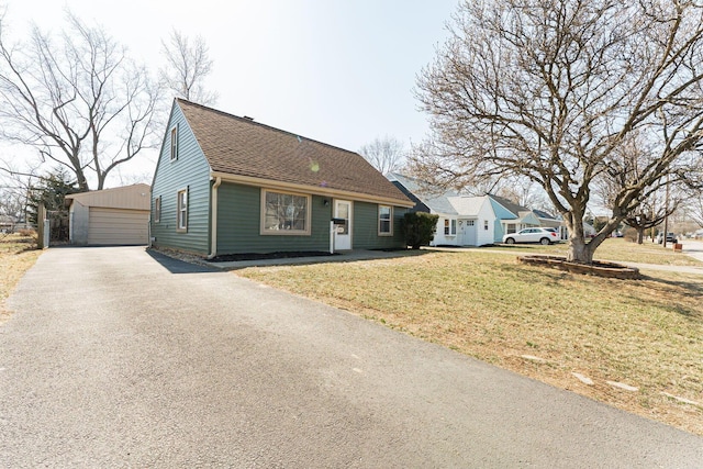 view of front of house with an outdoor structure, a garage, a front lawn, and roof with shingles