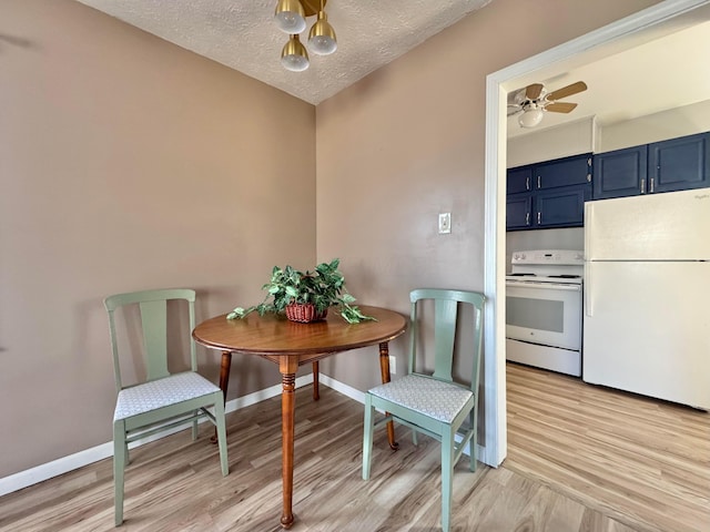 dining room featuring a textured ceiling, light wood-style floors, baseboards, and ceiling fan