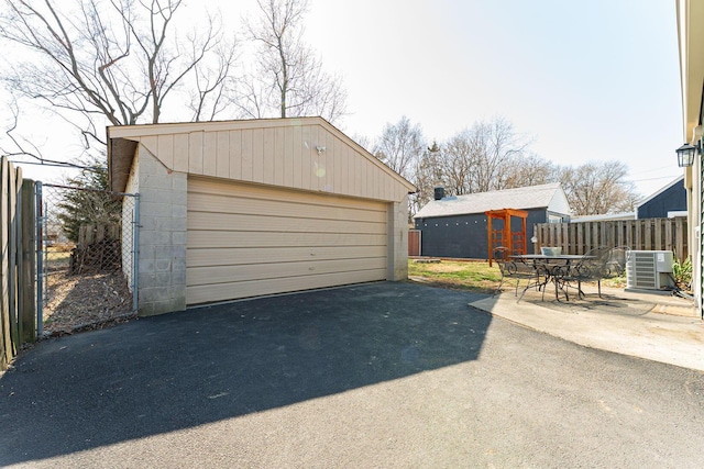 detached garage featuring cooling unit and fence