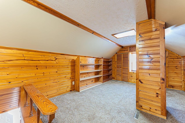 bonus room with wood walls, a textured ceiling, and lofted ceiling