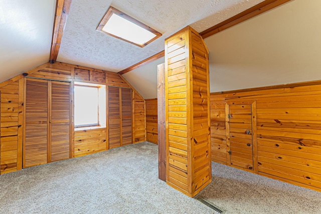 additional living space featuring vaulted ceiling, wood walls, and a textured ceiling