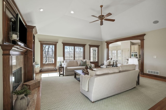 living room with a high end fireplace, visible vents, a wealth of natural light, and wood finished floors