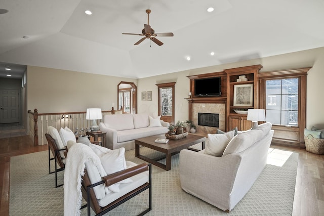 living area with wood finished floors, a premium fireplace, recessed lighting, ceiling fan, and vaulted ceiling