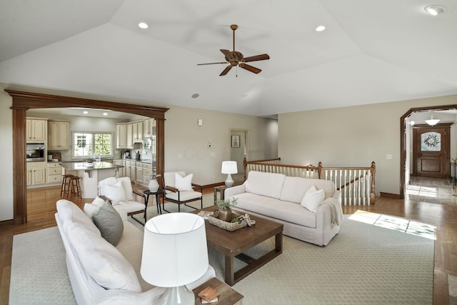 living area with baseboards, vaulted ceiling, recessed lighting, arched walkways, and a ceiling fan