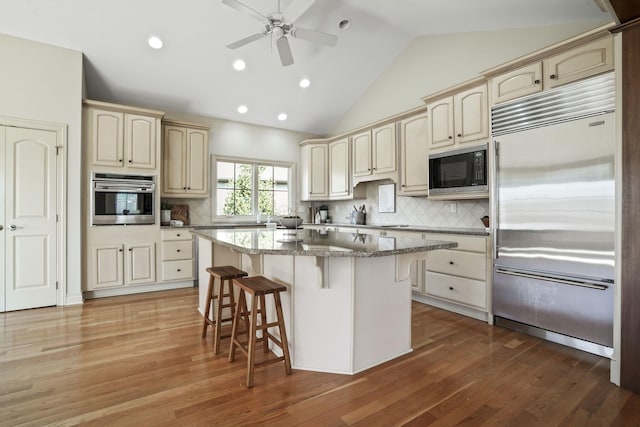 kitchen featuring built in appliances, cream cabinets, and a kitchen bar