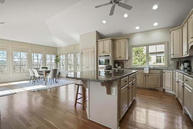 kitchen featuring stainless steel oven, decorative backsplash, a kitchen island, and a breakfast bar