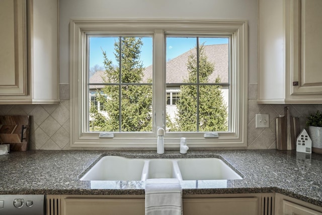 kitchen with a sink, dark stone counters, and a healthy amount of sunlight