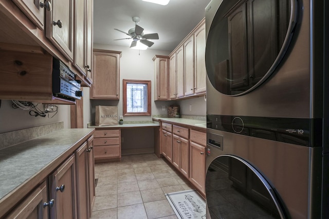 kitchen featuring light countertops, light tile patterned floors, a ceiling fan, and stacked washer / drying machine