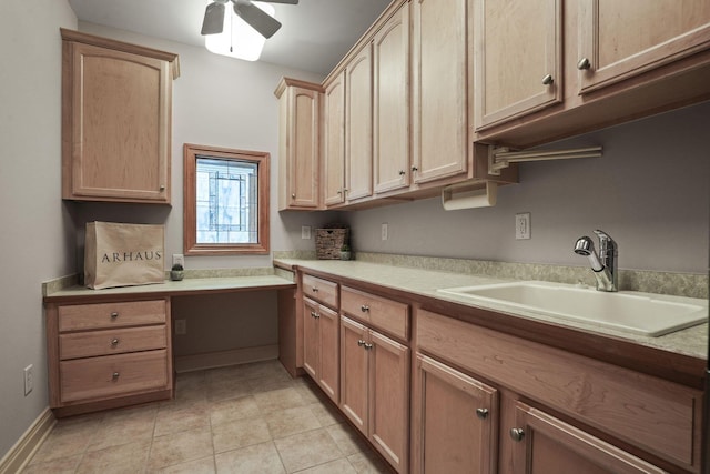 kitchen featuring a ceiling fan, light brown cabinetry, a sink, light countertops, and built in desk