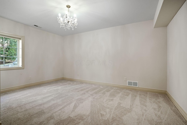 spare room with an inviting chandelier, baseboards, visible vents, and carpet floors