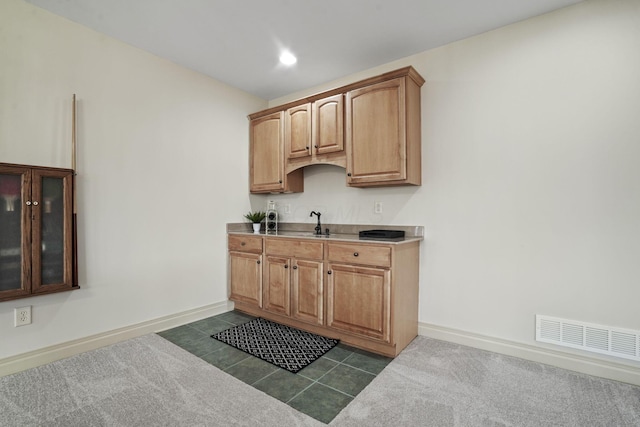 kitchen featuring baseboards, visible vents, a sink, dark tile patterned floors, and dark carpet