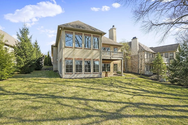 rear view of property with stucco siding, a lawn, and a chimney