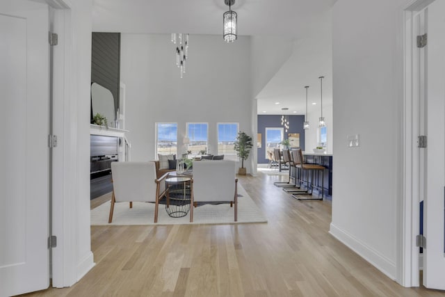 dining room with a chandelier, baseboards, a high ceiling, and wood finished floors