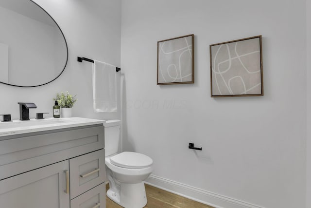 bathroom featuring vanity, toilet, wood finished floors, and baseboards