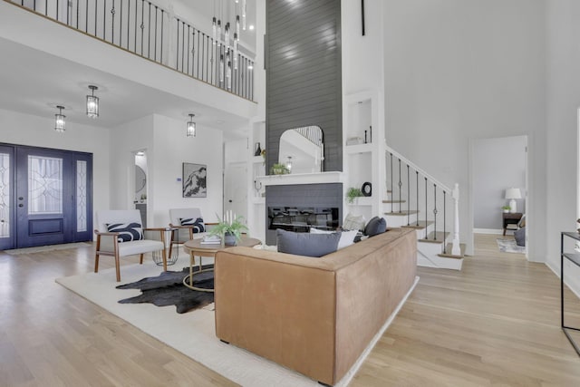 living area featuring a towering ceiling, stairway, wood finished floors, and a fireplace