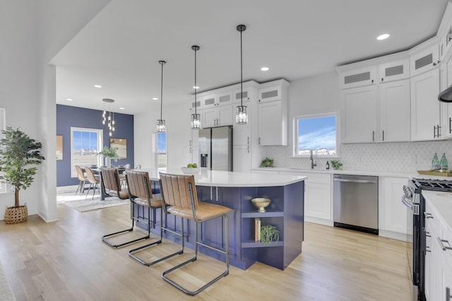 kitchen featuring decorative backsplash, white cabinets, a kitchen island, and stainless steel appliances