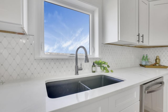 kitchen featuring tasteful backsplash, white cabinets, dishwasher, and a sink