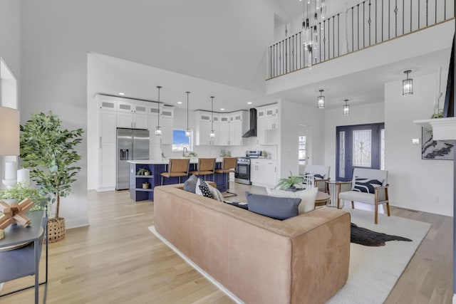 living area with plenty of natural light, baseboards, light wood-type flooring, and a towering ceiling