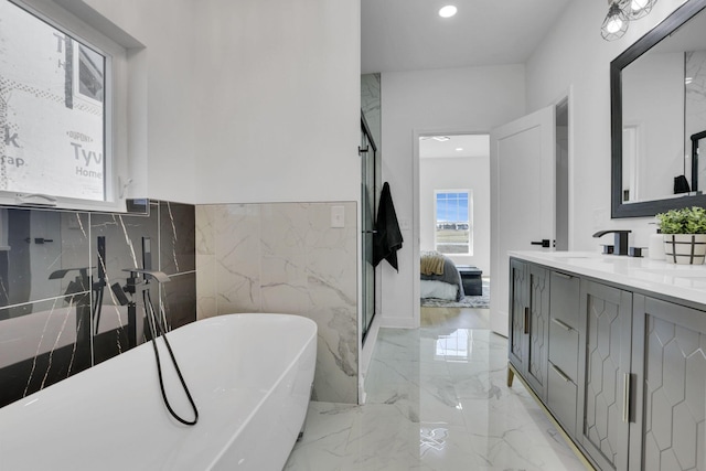 ensuite bathroom featuring a freestanding tub, marble finish floor, a sink, ensuite bath, and double vanity