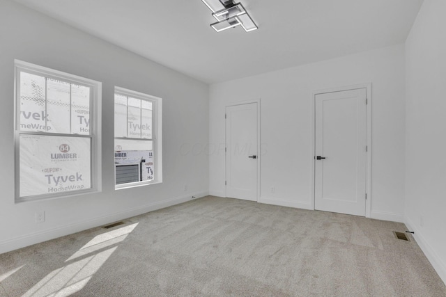 unfurnished bedroom with two closets, baseboards, visible vents, and carpet floors