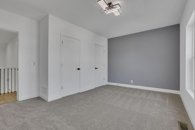 unfurnished bedroom featuring visible vents, carpet floors, and baseboards