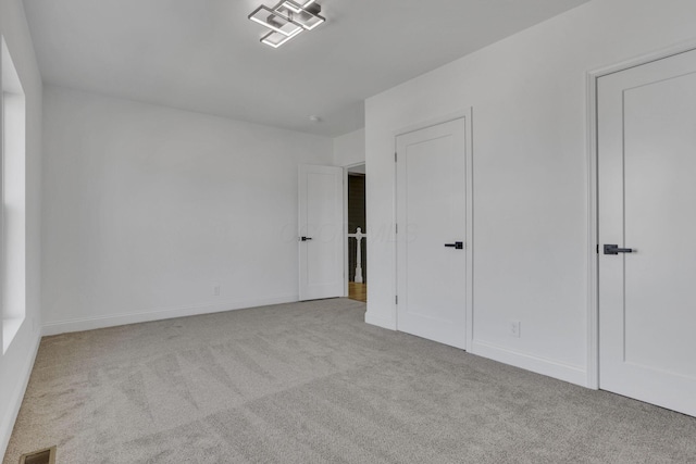 unfurnished bedroom featuring visible vents, carpet floors, and baseboards