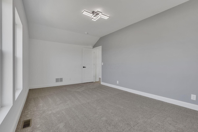 unfurnished room featuring visible vents, baseboards, lofted ceiling, and carpet floors