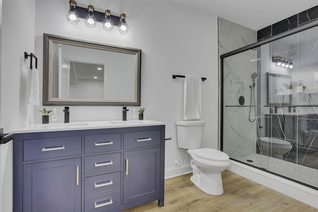 full bathroom featuring a sink, a marble finish shower, toilet, and wood finished floors