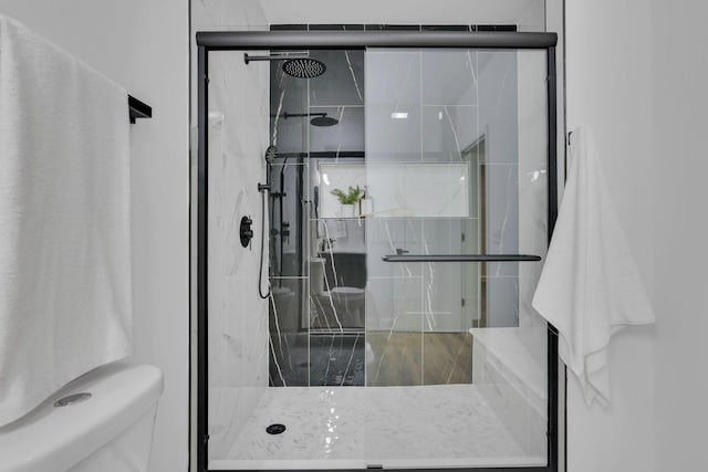 full bath with a marble finish shower and toilet