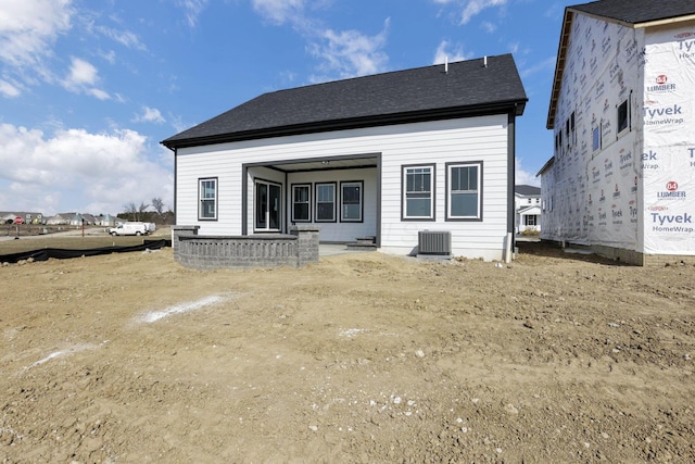 rear view of property with central air condition unit and roof with shingles