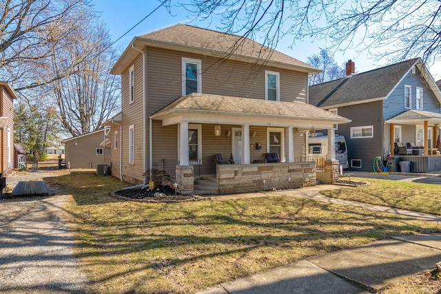 american foursquare style home featuring central air condition unit, a porch, a front lawn, and a shingled roof